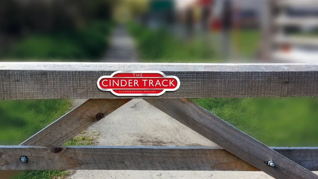 The Cinder Track logo signage on a country gate